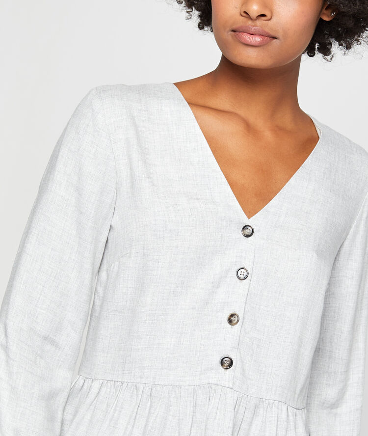 Blouse boutonnée à volants gris chiné clair.
