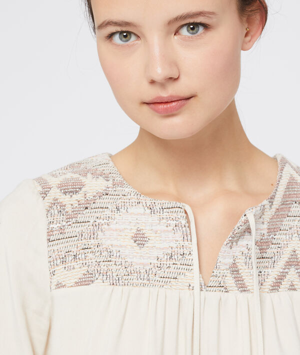 Blouse à pompons beige.
