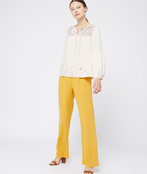 Blouse à pompons beige.