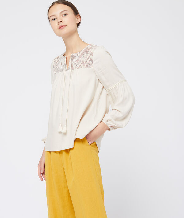 Blouse à pompons beige.